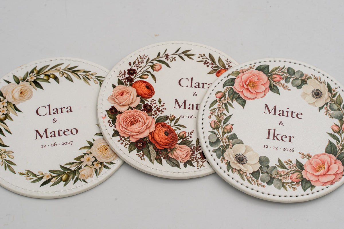 Tres posavasos redondos brancos con flores a cor e nomes dos noivos.