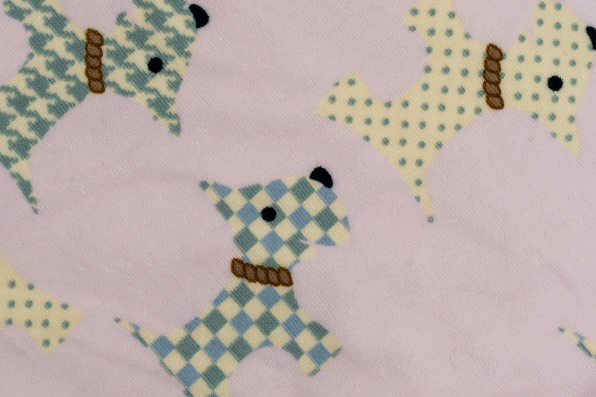 Detalle de toalla rosa con dibujos de perros tipo terrier con patrones geométricos.