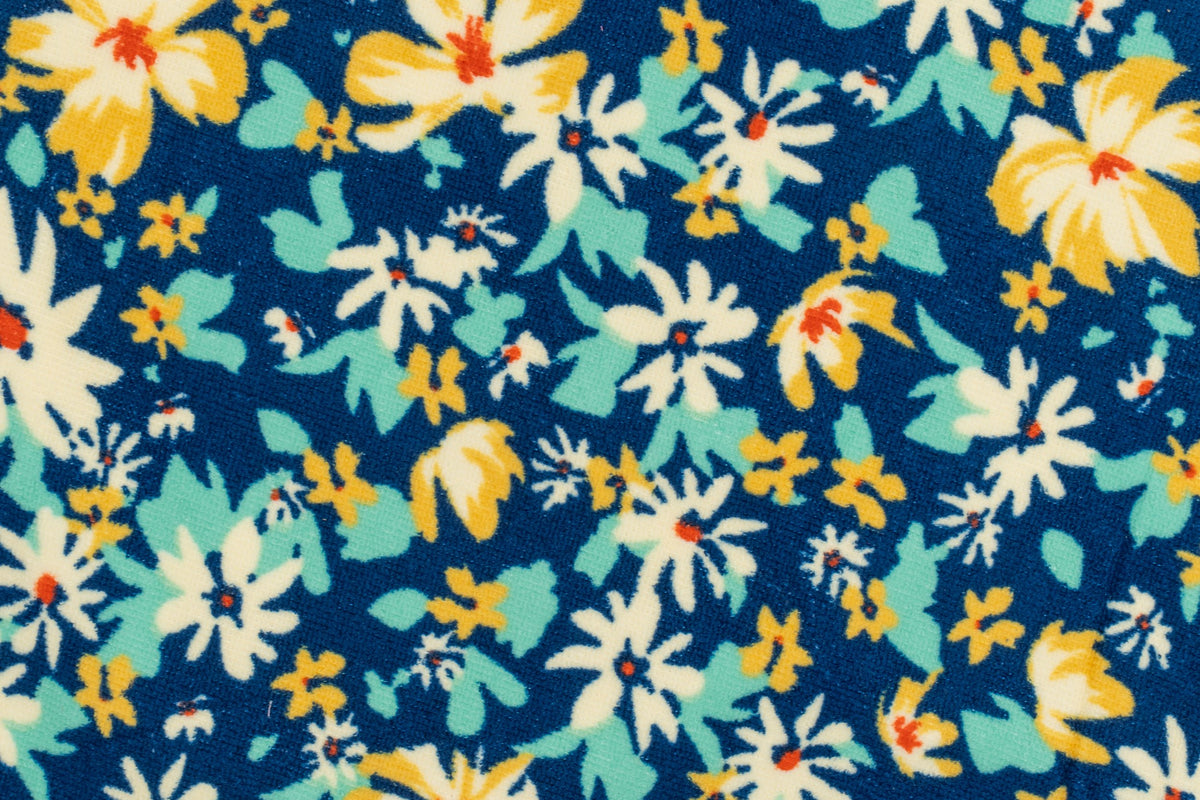 Primeiro plano dunha toalla azul mariño con flores brancas e amarelas estampadas.