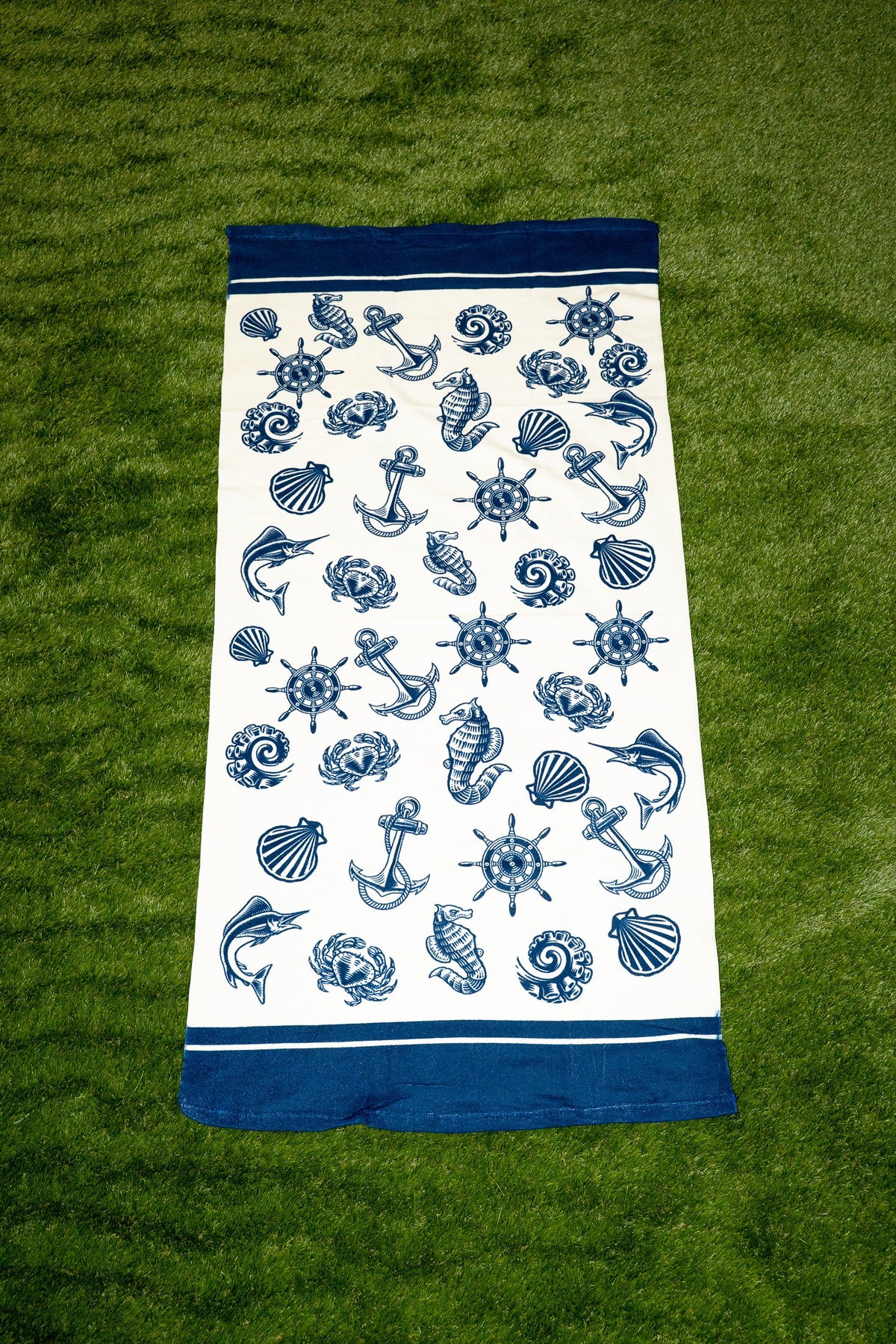 Toalla branca con estampado náutico azul de áncoras, cunchas e temóns.