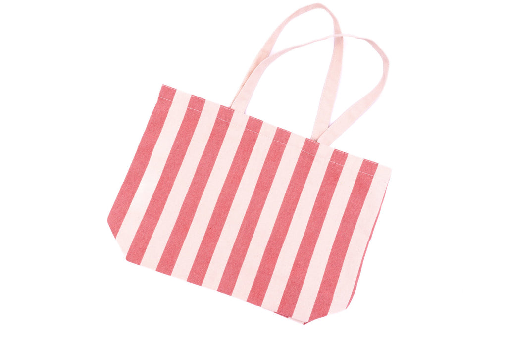 Bolso de praia de algodón con raias rosas e brancas visto en plano xeral.