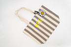 Bolso para a piscina con raias grises e brancas decorado cun colgante de margarida.