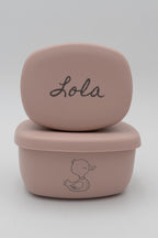 Dos tuppers rosa apilados con el nombre Lola y dibujo de pato