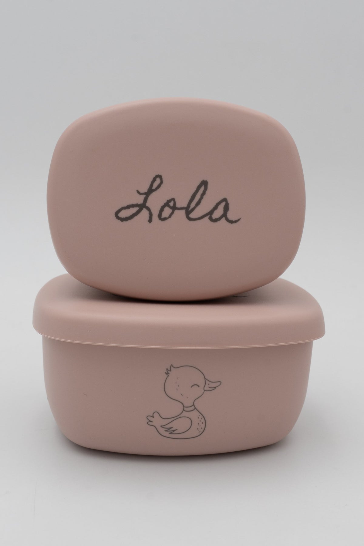 Dos tuppers rosa apilados con el nombre Lola y dibujo de pato